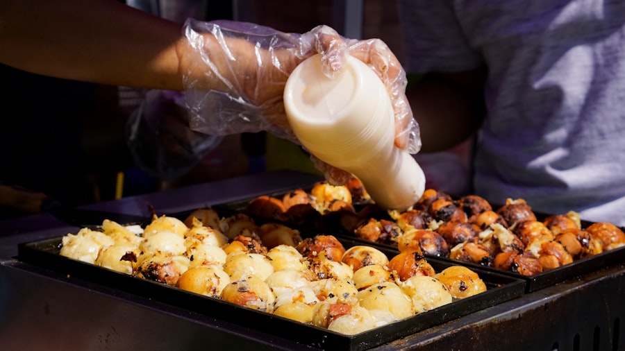 鉄板の上のたこ焼きにマヨネーズをかける様子